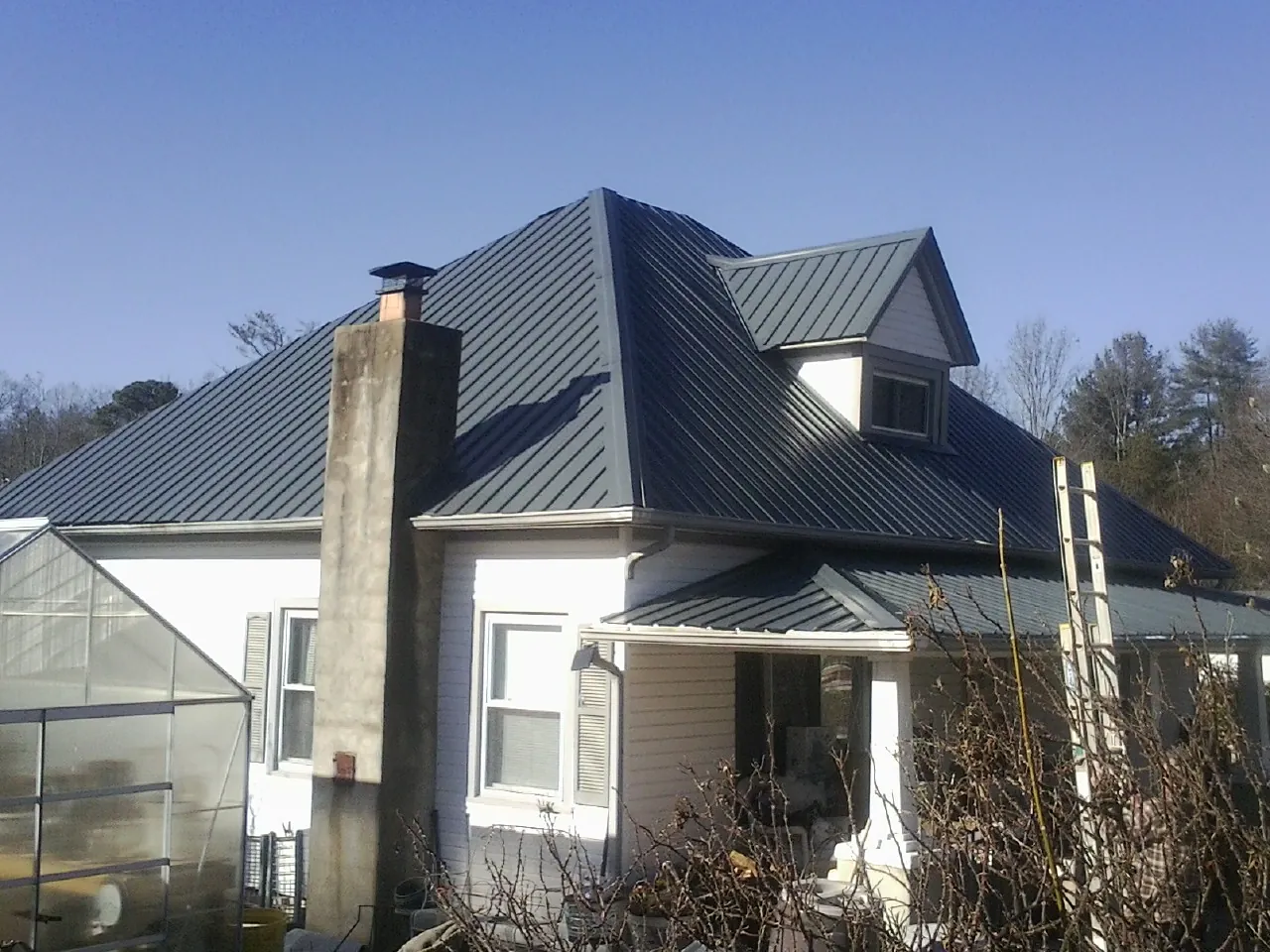 Dark blue standing seam metal roof on a white farmhouse with dormer — Slate & Tile Roof Repair by Roofing Brothers in Kenai