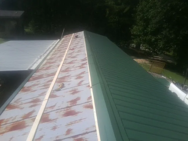 Old rusted panels beside newly installed green metal roofing — Wind Damage Roof Repair by Roofing Brothers in Kenai