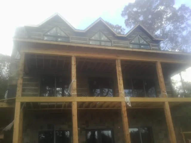 Dormers and porch framing on a large log home under construction — Roof Coating work by our crew in Kenai